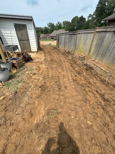 Site prep, the backyard graded to bare dirt along the fence line