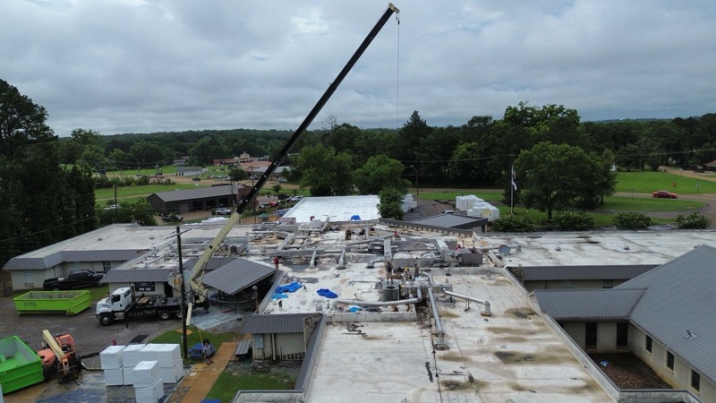 Crane over a low-slope commercial roof mid replacement