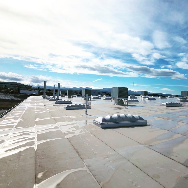 A finished white membrane commercial flat roof with skylights and rooftop units