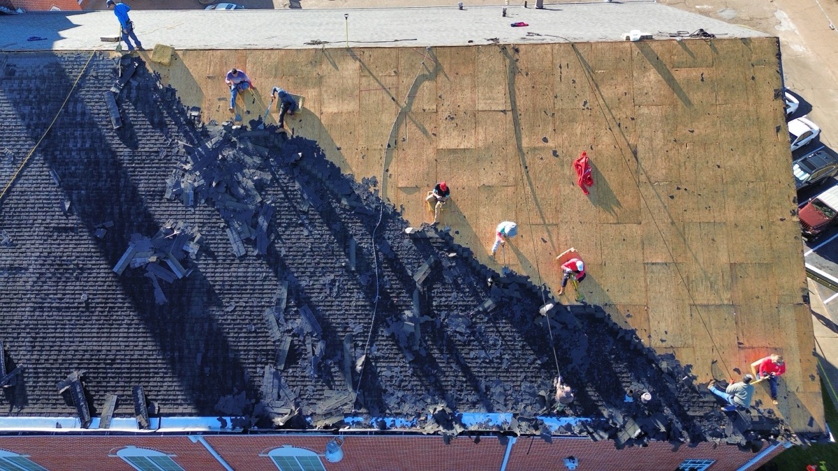 Overhead view of the full Dickerson crew spread across a steep roof mid tear-off